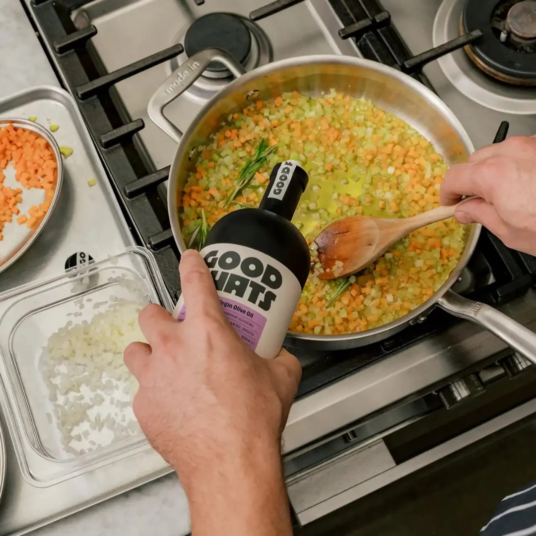 Spanish extra virgin olive oil being poured into a pan with diced vegetables during gentle cooking